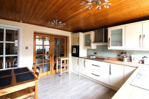 a kitchen with white cabinets and a wooden ceiling at St James's Rd in Belfast