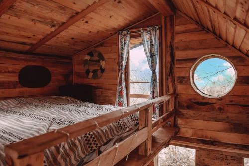 a bedroom in a log cabin with a bed and a window at Apple Tree Cabin (Friendship Land) 