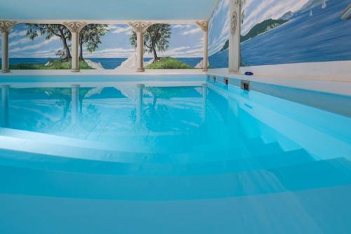 a swimming pool with blue water and palm trees at Hafenhotel zu Putbus in Putbus