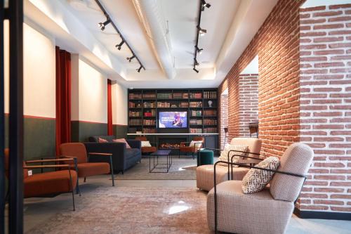 a lobby with chairs and a tv and a brick wall at LATROUPE Prado Hostel in Madrid