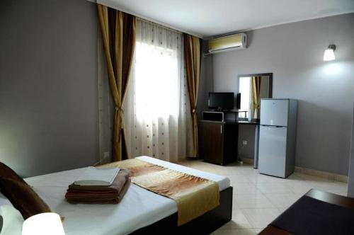a bedroom with a bed with a refrigerator and a window at Calla Inn Hotel in Constanţa