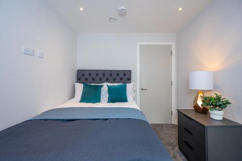 um quarto com uma cama grande e almofadas azuis em Cosy 3 Bed by Old Trafford By Valore Property Services em Manchester