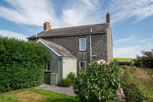 an old brick house with a bush in front of it at Rosehip Cottage in Holbeton