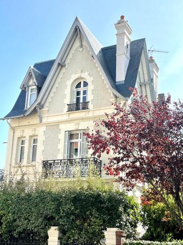 une grande maison blanche avec un toit à la mansarde dans l'établissement 77 VH - Villa piscine - plein centre, à Deauville