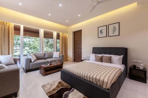 a large bedroom with a bed and a couch at Inara by StayVista - Amidst lush greenery with Outdoor swimming pool & Indoor games in Lonavala