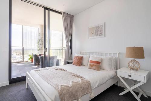 a white bedroom with a bed and a large window at The Occidental Pearl in Sydney