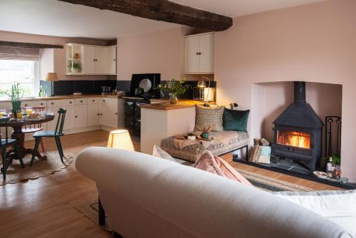 a kitchen and a living room with a fireplace at Wild Rose Cottage in Holbeton