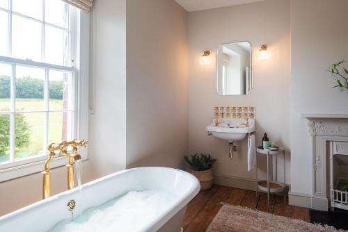 a white bathroom with a tub and a sink at Wild Rose Cottage in Holbeton