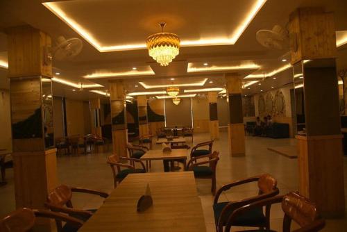 Habitación grande con mesas, sillas y lámpara de araña. en Shiva Palace by Golden Leaf Hotels, en Haldwāni