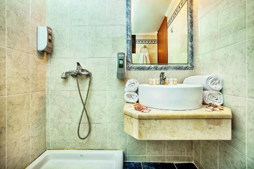 ein Badezimmer mit einem Waschbecken, einem Spiegel und einer Badewanne in der Unterkunft Elinotel Polis Hotel in Chaniotis