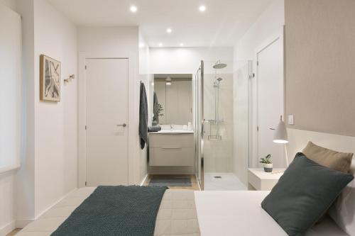 a white bedroom with a large bed and a bathroom at Mirador del Portillo in Zaragoza