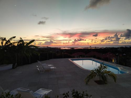 puesta de sol sobre una piscina en un patio en Holiday Home Belvedere en Dickenson Bay