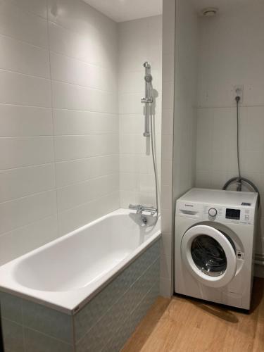a white bath tub with a washing machine in a bathroom at LES 3 MARMOTS in Gérardmer