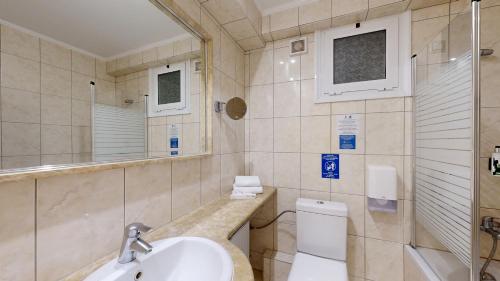 a bathroom with a sink and a toilet and a mirror at Lucy Hotel in Chalkida