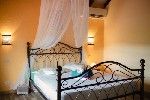 1 dormitorio con cama negra con sábanas blancas en Domaine Babwala, villa et bungalow avec piscine dans un superbe jardin tropical #cosy, en Saint-Louis