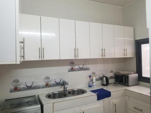 a kitchen with white cabinets and a sink and a microwave at Villa Ndiaye in Ngaparou