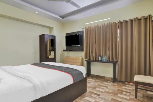 Schlafzimmer mit einem Bett, einem TV und Vorhängen in der Unterkunft Collection O Hotel Starfield in Lucknow