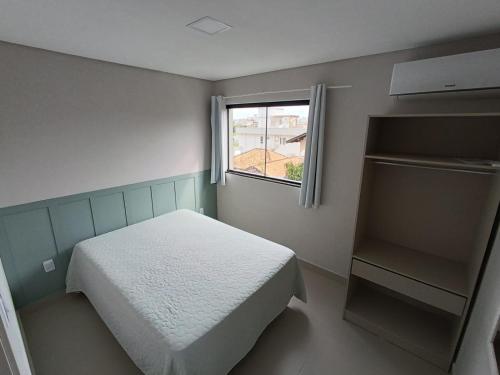 a small bedroom with a bed and a window at Residencial Brisa do Mar in Bombinhas