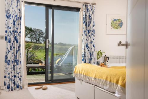 1 dormitorio con 1 cama y puerta corredera de cristal en St Ia, Castle Approach, Tregenna Castle, en St Ives