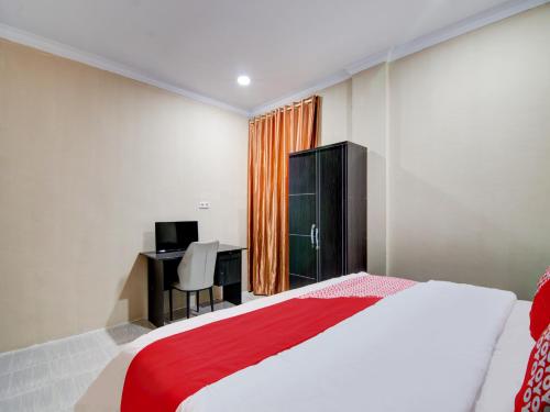 1 dormitorio con 1 cama y escritorio con ordenador en OYO 93087 Wisma Apel Syariah, en Parit