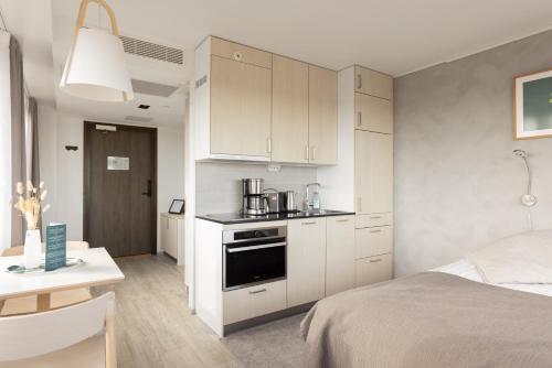 a kitchen with white cabinets and a bed in a room at Noli Sörnäinen in Helsinki