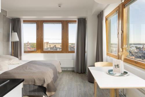 a hotel room with a bed and a desk and windows at Noli Sörnäinen in Helsinki