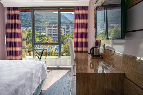 a hotel room with a bed and a desk and windows at TOK EPİK HOTEL in Bursa