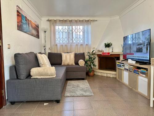 a living room with a couch and a flat screen tv at Cascais Quaint Cottage in Alcabideche