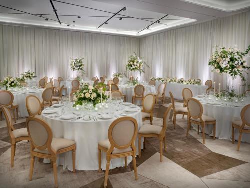 a room filled with tables and chairs with flowers at The Westin London City in London