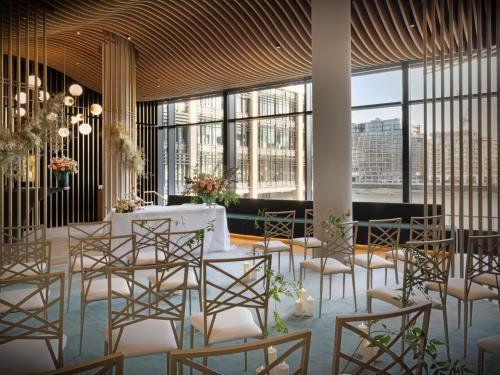 a room with a table and chairs and large windows at The Westin London City in London