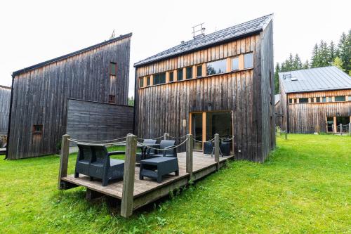 a wooden deck with two chairs and a building at Horská chata Harrachov in Harrachov