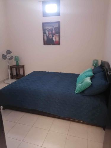 um quarto com uma cama com lençóis e almofadas azuis em app à Tamraght prés de la plage de 100m em Agadir