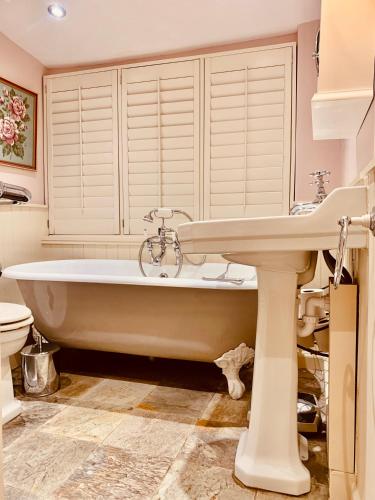La salle de bains est pourvue d'une baignoire blanche et d'un lavabo. dans l'établissement Rose Cottage - 17th Century Idyllic Country Cottage in Picturesque Village with Great Pub, 