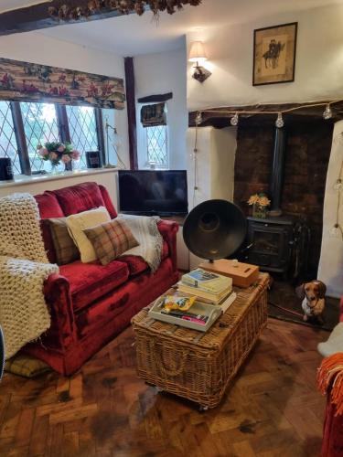 a living room with a red couch and a fireplace at Rose Cottage - 17th Century Idyllic Country Cottage in Picturesque Village with Great Pub 