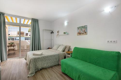 Un dormitorio con una cama y un sofá verde. en Estudio Sagrario, en Arona