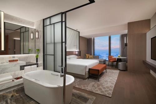 a hotel room with a bed and a tub and a bedroom at Hyatt Regency Changshu Kuncheng Lake in Changshu
