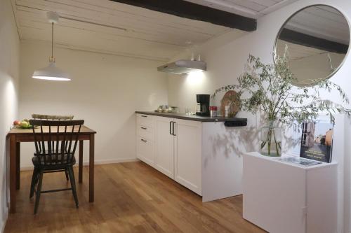 cocina con armarios blancos, mesa y espejo en Cosy guesthouse in the countryside, with breakfast, en Malmö