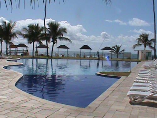 ein Swimmingpool mit Liegestühlen und Sonnenschirmen in einem Ferienresort in der Unterkunft Ancorar Porto de Galinhas in Porto De Galinhas