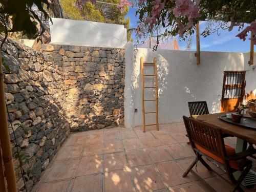 a stone wall with a ladder next to a table at Boutique Hostal La Curandera de Salinas in Ibiza Town