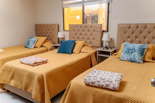 a room with three beds with yellow sheets and blue pillows at 2 Cabañas para 5 Personas Oasis Pica-Matilla in Pica