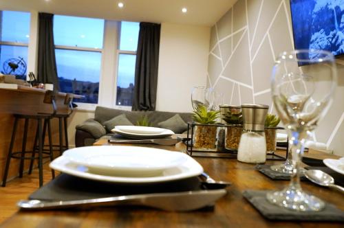 a dining room table with plates and glasses on it at Grace House Apartment - Yorkshire in Keighley