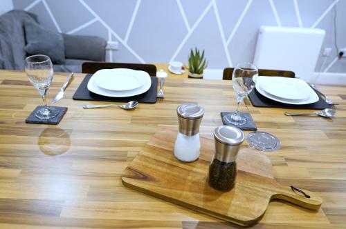 a wooden table with plates and wine glasses on it at Grace House Apartment - Yorkshire in Keighley