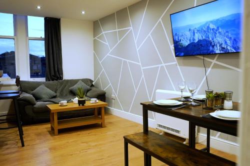 a living room with a couch and a tv on a wall at Grace House Apartment - Yorkshire in Keighley