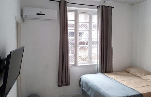 1 dormitorio con 1 cama y una ventana con cortinas en Pousada Central - Prox da Rodoviaria, Shoping Total, Hosp Santa Casa e Presidente Vargas en Porto Alegre