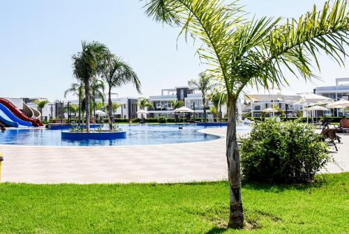 a swimming pool with a slide and a palm tree at Luxury Four Seasons Life Sea Front Apartment 6-C in Boğaz