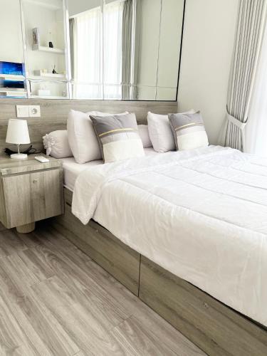 a large bed with white sheets and pillows in a bedroom at Apartement 2BR sky house BSD in Cilenggang