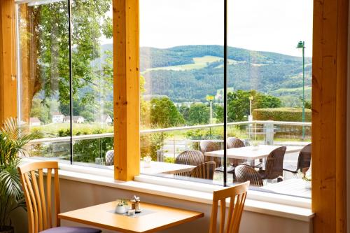 a restaurant with a view of the mountains through windows at JUFA Hotel Garni Stubenberg am See in Stubenberg