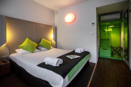 a bedroom with a large bed with green accents at Campanile Hotel & Restaurant Liège / Luik in Liège