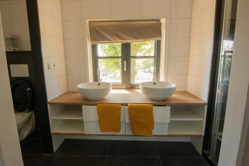 Baño con 2 lavabos en un estante con ventana en Grazelands - overnachten midden in de natuur, 