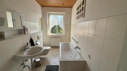 a white bathroom with a sink and a toilet at Bitterfelder Cityapartment im Dichterviertel in Bitterfeld